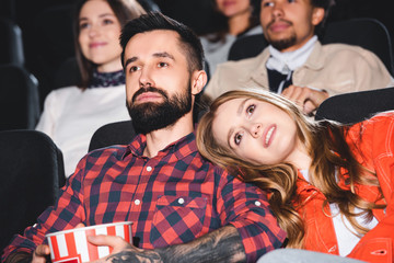 Fototapeta premium attractive girlfriend lying on shoulder of handsome boyfriend and watching movie in cinema