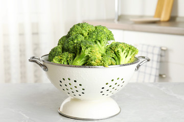 Raw green broccoli in colander on light grey marble table indoors - obrazy, fototapety, plakaty