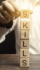 A man puts wooden blocks with the word Skills. Knowledge and skill. Self improvement. Education...