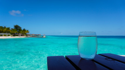 Clear glass water cocktail with blue turquoise ocean background