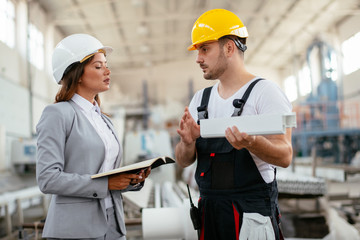 Architect and worker working on project. Colleagues discussing work in factory.