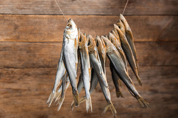 Dried fish hanging on rope against wooden background