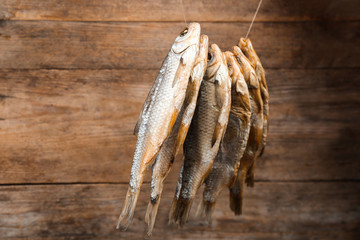 Dried fish hanging on rope against wooden background