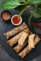 Above view of traditional vietnamese fried spring rolls or nems with dipping sauces on a stone...