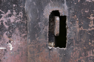 A close up shot of an old rusted key on a metal door keyhole.