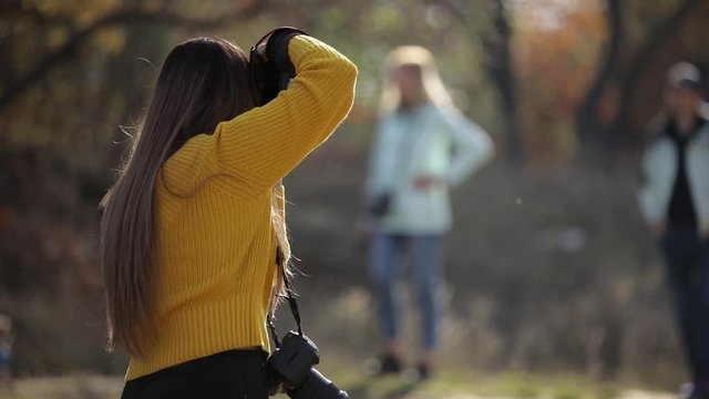 young woman photographer takes pictures of model in nature in autumn. the photographer in action