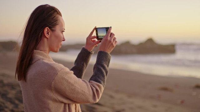 Woman taking picture of a sunset near ocean