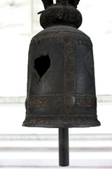 A black metal bell broken into a hole hanging in a thai temple