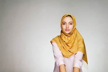 Muslim woman with a calm face in a yellow shawl in a bright studio