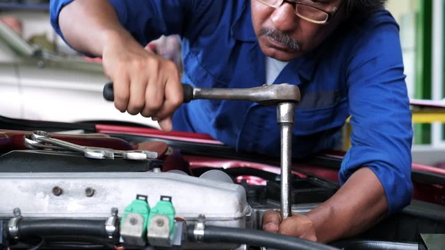 Auto mechanic tighten bolt of engine car with torque wrench in automobile garage.maintenance and adjustment 