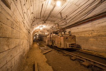 Fototapeta na wymiar Gold iron mine ore shaft tunnel drift with rails electric locomotive