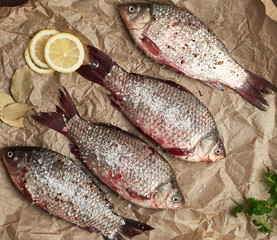 whole fresh crucian fish with scales on a crumpled brown piece of paper