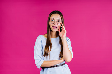 girl in a pink studio with an expression of curiosity in her face looks through glasses for vision