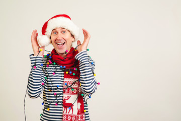 Handsome guy in Santa claus hat with garlands on him. Christmas sales, discounts and shopping