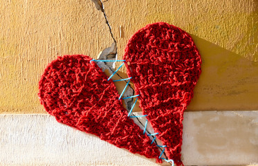 Fototapeta na wymiar Cracked wall with sewed heart on the street