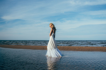 Fototapeta na wymiar Portrait of young blond bride staying among the water