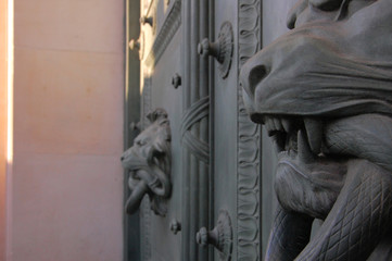 door knockers in shape of lion head with a snake in its mouth on massive gates in Paris, France