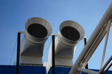 white ventillation tubes on black roof against blue sky background