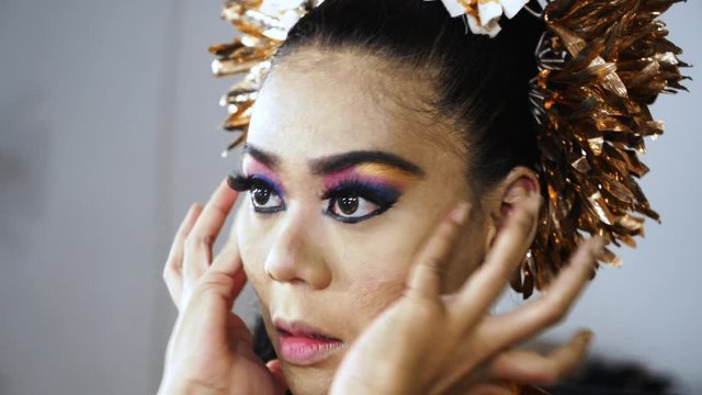 Balinese dancer applying makeup with her fingers on her face in makeup room. Shot in 4k resolution