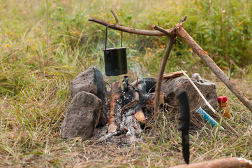 Cooking in sooty cauldron on campfire at forest