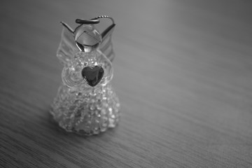 Little angel figurine with a heart on the table. Holiday toy. Bw photo