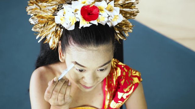 Balinese dancer coloring her eyebrow in makeup room. Shot in 4k resolution