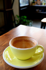 Vertical image of an empty cup of finished drinking coffee isolated on cafe's wooden table