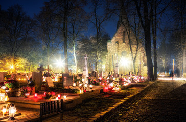 Naklejka na ściany i meble Burning candles on graves during All Saints Day