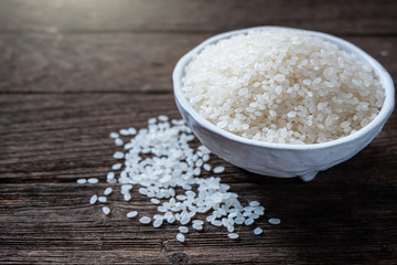 Japanese rice in a cup and on the wooden floor. Close up shot. Top view.