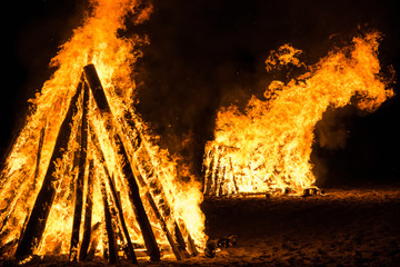 Cone shaped bonfires with big flames and wood