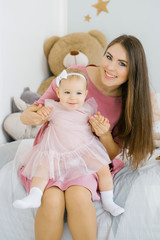 a one-year-old girl is a child in her mother's arms. Happy smiling mom and daughter