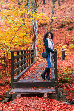 Young woman on a small wooden bridge in a forest at autumn. River and camping place Grza near the Paracin in Serbia.