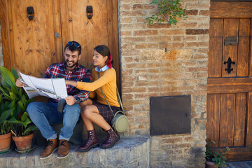 Man and woman traveling and reading map in city of location