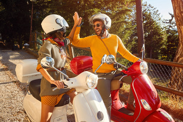 Happy couple laughing and riding a scooter outdoors