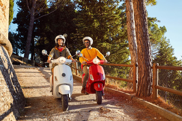 Happy man and woman laughing and riding a scooter outdoors © luckybusiness