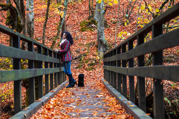 Young woman on a small wooden bridge in a forest at autumn. River and camping place Grza near the Paracin in Serbia.