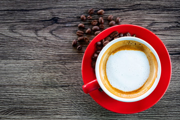 Top view red coffee cup and coffee bean on wood table near window with light shade on tabletop at cafe.