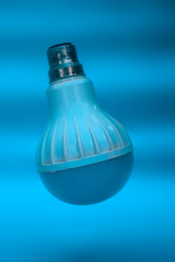 White and Blue colored LED Bulbs isolated on blue glossy background.