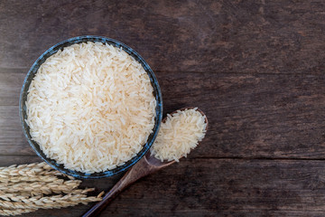 Parboiled rice in ceramic cups and wooden spoons on a wooden table. Close up shot.
