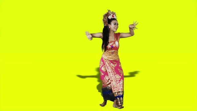 Full length of pretty balinese dancer in traditional costume dancing in the studio with yellow background. Shot in 4k resolution
