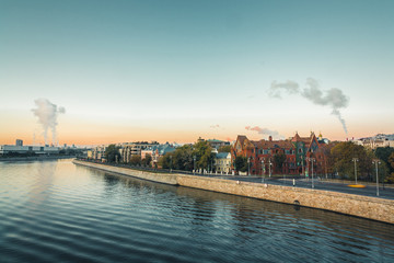 Fototapeta premium Morning city landscape with view on Moscow river and embankment in old part of city. Gentle blue sky in the rays of the rising sun and smoke from the chimneys