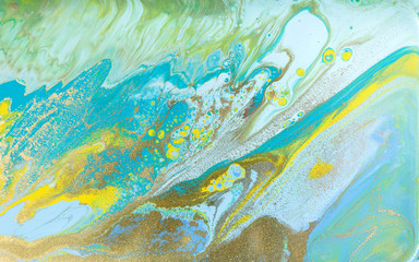 Yellow and blue pastel marble pattern with golden glitter. Abstract liquid background.