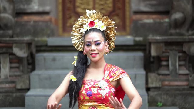 Slow motion of attractive balinese dancer showing a welcoming gesture while wearing traditional costume in the temple