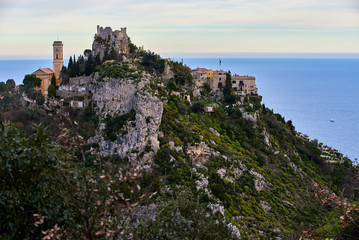 Fototapeta na wymiar Èze Village at the French Riviera during sunset. Village on top of a steep hill with cliffs towards the sea. Ocean and clouds in the background.