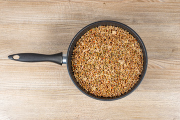 Freshly cooked buckwheat porridge with minced pork on a wooden table