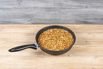 Freshly cooked buckwheat porridge with minced pork on a wooden table