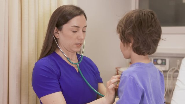 A pediatric nurse with a young patient as she checks his vitals.
