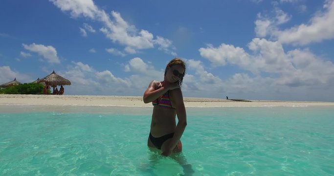 woman standing in ocean on luxury vacation in Bali, a girl wearing bikini and sunglasses