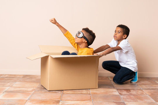African American brothers playing. Boy inside a cardboard box with aviator glasses