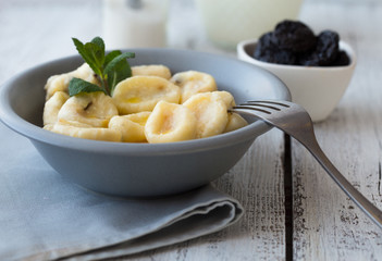 Lazy pierogi dumplings with sour cream and dry plums. and glass of milk.  Italian gnocchi